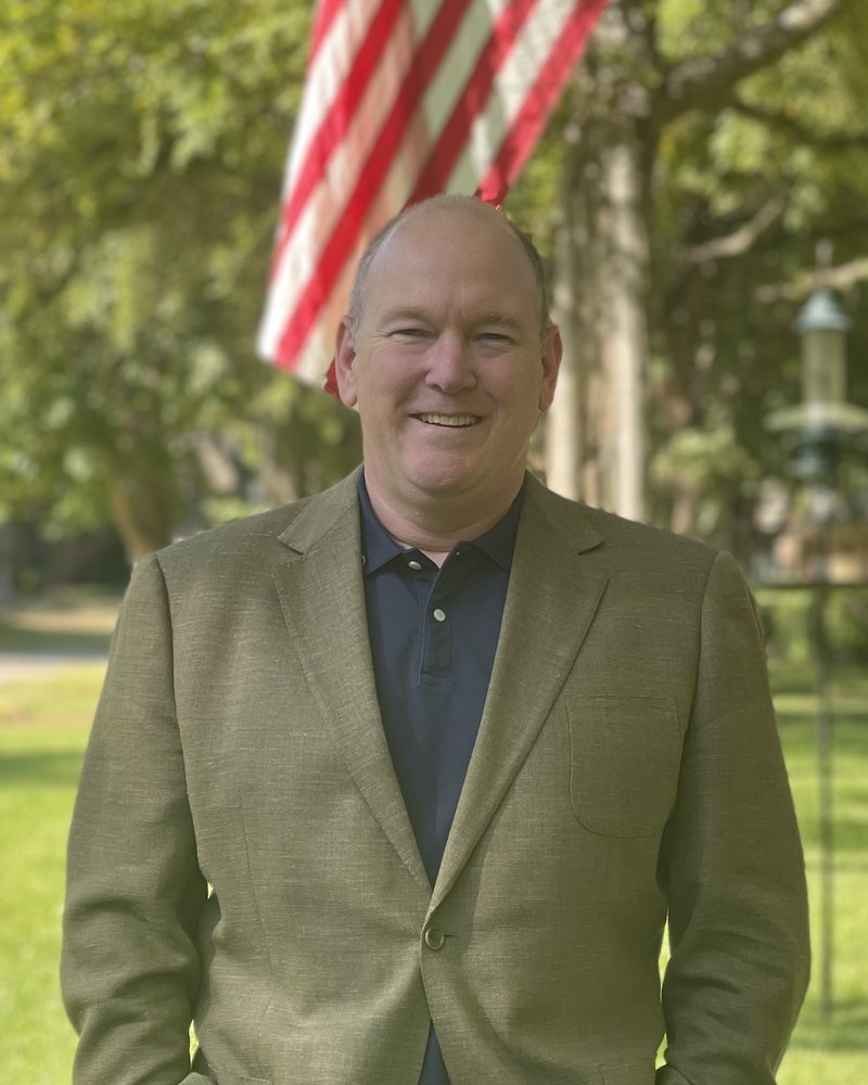 Derek, CFO, smiling outdoors in a green jacket